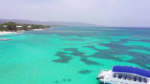 Boat moored in turquoise sea waters of Playa Ensenada beach, Dominican Republic. Aerial drone view