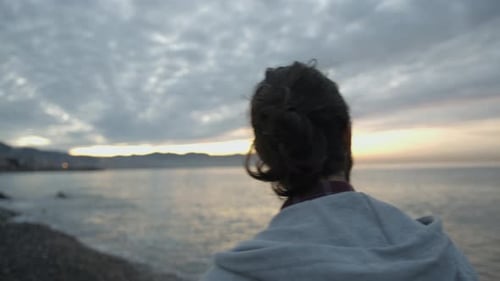 Hipster-Mann mit Brille spaziert am Meer, Blick auf Berg und Meer.