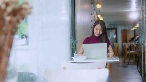 Woman Works on Laptop in a Modern Cafe