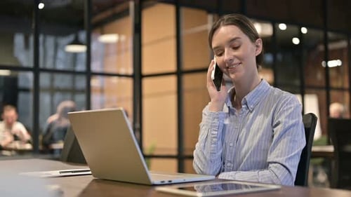 Woman Speaking on Mobile Phone in Office Setting