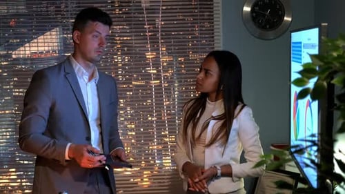 Two Colleagues Discussing Data in Office at Night