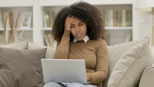 Woman Using Laptop Experiences a Headache