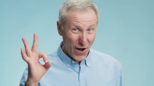 Man Smiling and Gesturing Okay on Blue Background