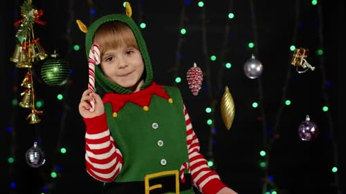 Festive Child Dressed as Elf Holding Candy Cane