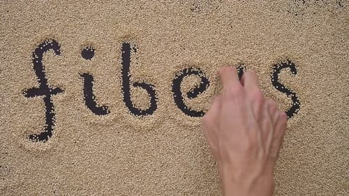 A Man Writes Text on a Black Background Using Quinoa Seeds