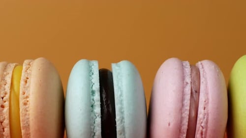 Multicolor Macarons, French macaroon, sweet tasty desserts. Isolated on a yellow background.