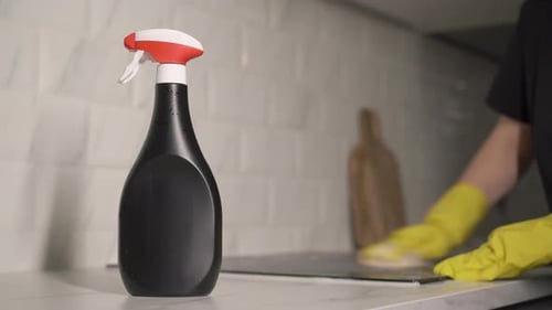 Woman Cleaning Kitchen Stove with Spray Bottle