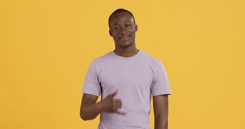 Man Gestures 'Call Me' on Yellow Background