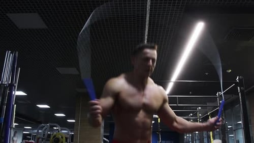Gym Training a Man with Fit Body Jumping Over the Rope