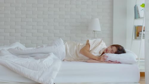 Beautiful Asian young woman close her eyes lying on bed and sleep in cozy bedroom