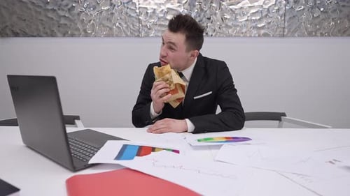 Man Eats Lunch While Working on Laptop