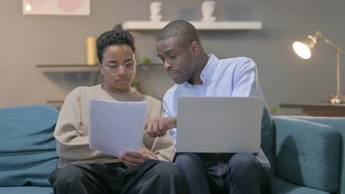 Woman and Man Reviewing Documents with Laptop