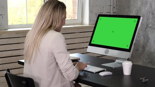 Business Woman in Dress Sitting on Workplace Near the Window and Using Computer in Office
