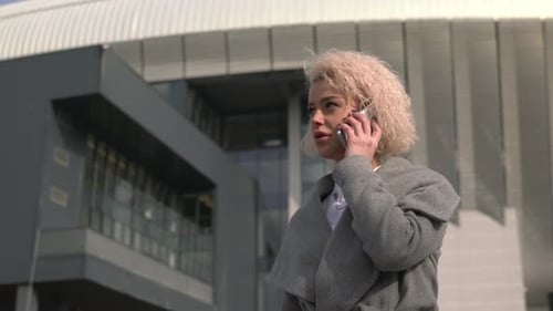 Woman Talking on Phone in Front of Building