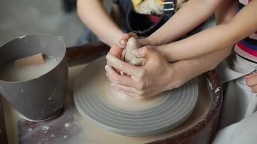 Hands molding clay on a pottery wheel