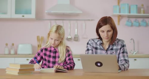 Preteen School Girl Making Homework and Mother Typing on Laptop. Family Stays at Home Together