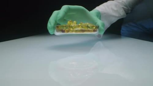 Labortechniker stellt Schale mit Ölkapseln auf weißen Tisch