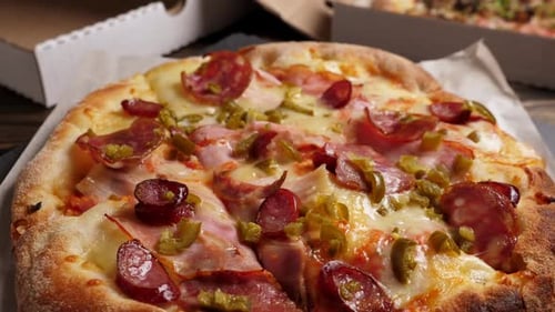 Una pizza de salami y tocino que gira sobre cajas con fondo de pizza
