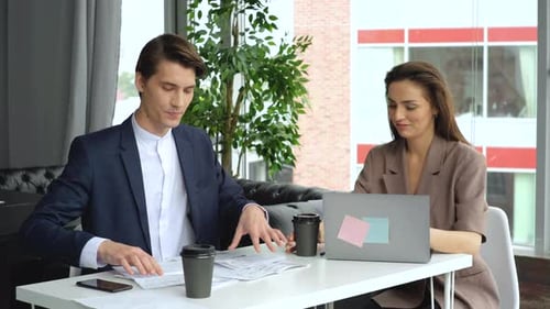 Belle jeune femme travaillant au bureau avec son collègue et ils boivent du café