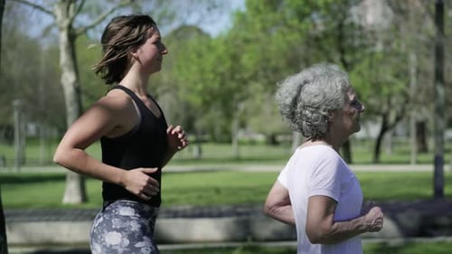 Young Woman and Senior Woman Jogging Through Park