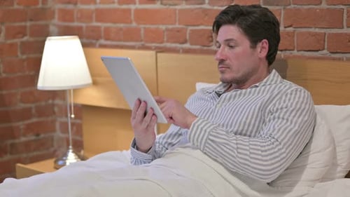 Man Using Tablet in Bed Relaxing