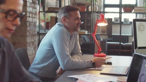 Two Male Colleagues Speaking at Coworking Table in Office