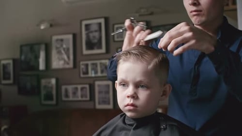 Hairdresser Cutting Young Boy's Hair in Home Salon
