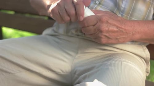 Senior Adult Pours Pills from Bottle Outdoors
