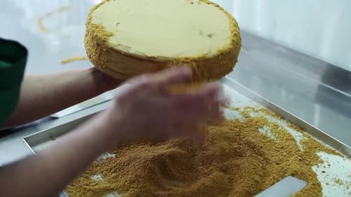 Baker Decorating Cream Cake with Crumbs