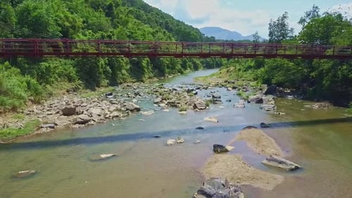 Flycam Moves Under Bridge Above River Against Highlands Sky