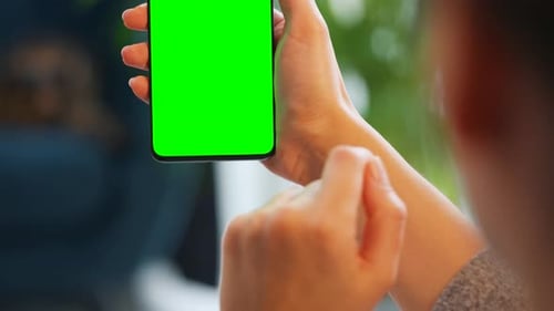 Woman at Home Using Smartphone with Green Mockup Screen in Vertical Mode
