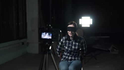 Relatif : Jeune femme otage avec un bandeau sur les yeux assise devant l'objectif d'une caméra