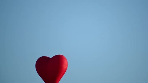 Red Heart Balloon Floats Freely in Blue Sky