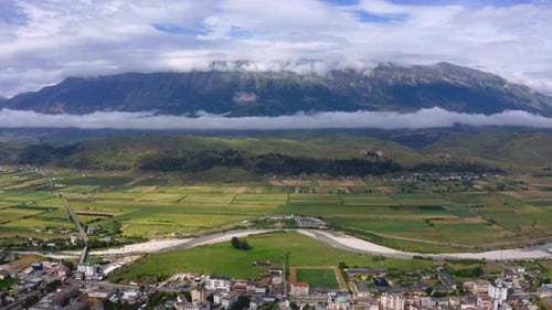 Drino river valley and balkan mountains with Gjirokaster town below. Aerial wide view