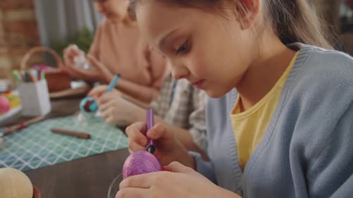 Jolie fille dessinant sur un œuf de Pâques avec un marqueur