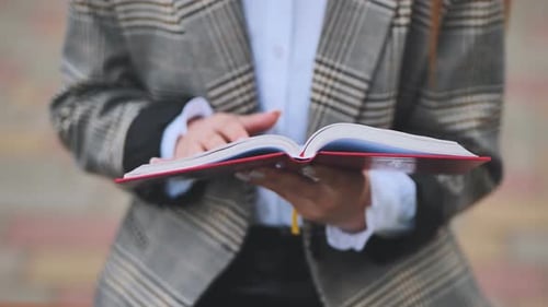 A Girl is Leafing Through a Book in the Park