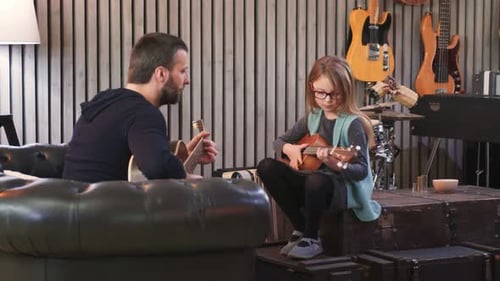 Father Teaching Girl to Play Ukulele in Music Room