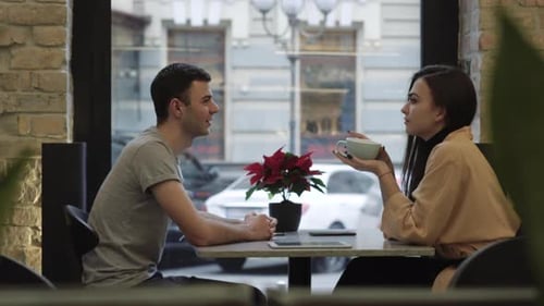 Side View of Positive Loving Boyfriend and Girlfriend Sitting and Cafe Talking