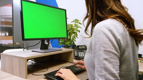 Woman at Desk Using Computer With Green Screen