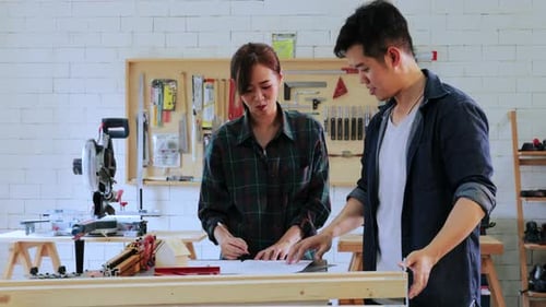 Two Carpenter workers working on workshop table in wood factory