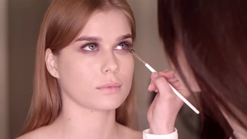 Makeup Artist Applying Eye Shadow to a Woman