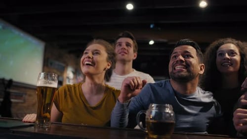 Group of friends cheering to soccer match in the pub. Shot with RED helium camera in 8K.