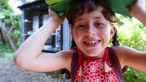 Portrait of schoolgirl carrying books overhead at school
