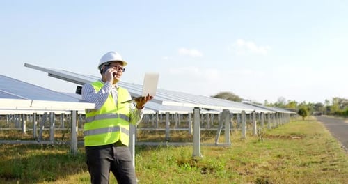 Young engineer talking on smartphone while working at solar farm
