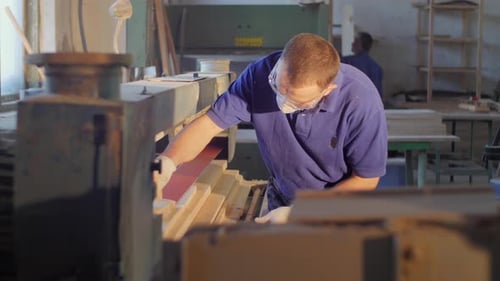 Man Sands Wood Planks in Carpentry Workshop