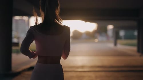 A Young Woman Runner is Training in the Summer Within a City