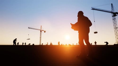 Silhouettes of Construction Workers and Cranes at Sunset