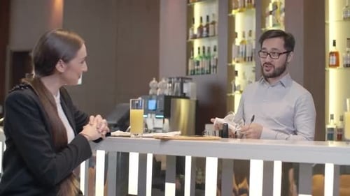 Woman Drinking Juice Talking with Bartender in Bar