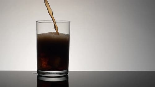 Cola Poured Into Glass Over Ice Cubes