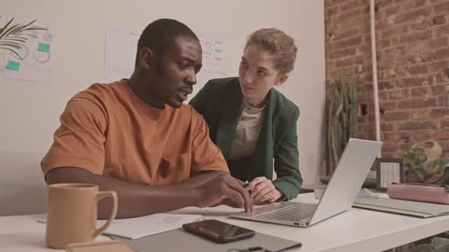 Teamwork in Modern Workplace: Colleagues Collaborate on Laptop